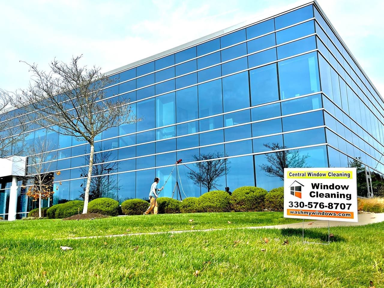 Commercial window cleaning technician using a water-fed pole on a glass office building exterior, Akron OH area