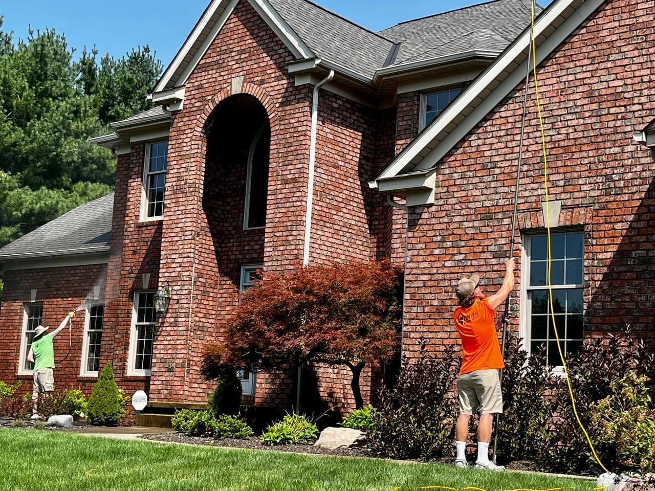 Central Window Cleaning technicians cleaning windows on a two-story brick residential home, Akron OH area
