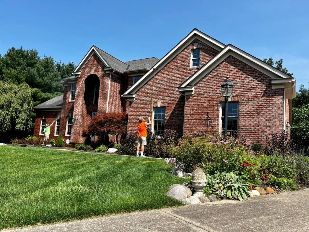 Two Central Window Cleaning technicians washing windows on a brick residential home, Akron OH area